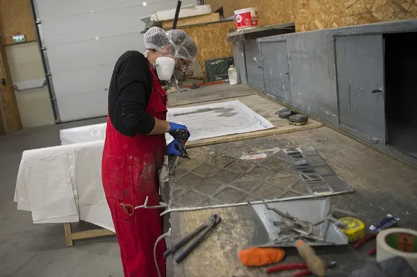 Séparation des joints de plomb d'un vitrail abîmé par le temps chez un restaurateur de vitraux
