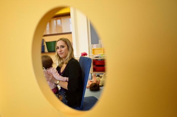 Auxiliaire de puériculture s’apprêtant à donner le biberon dans une crèche