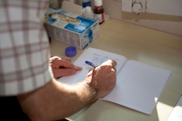 Infirmier renseignant le cahier de liaison au domicile d’un patient