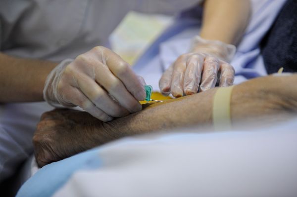Infirmière au lit d’un patient à son domicile effectuant un prélèvement