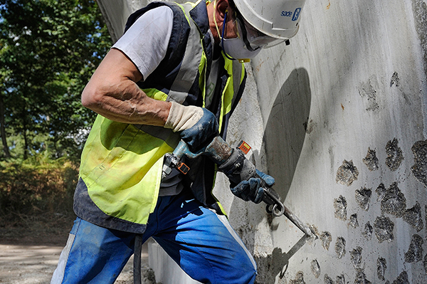 Travailleur utilisant un piqueur sur un chantier de BTP Travailleur utilisant un piqueur sur un chantier de BTP