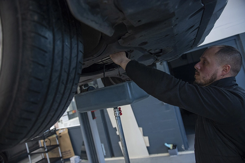 Un salarié travaille sous une voiture, les bras en l'air. Un salarié travaille sous une voiture, les bras en l'air.