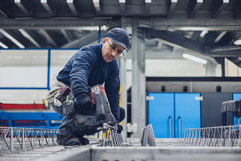 Un salarié travaille accroupi avec à la main une machine-outil Un salarié travaille accroupi avec à la main une machine-outil